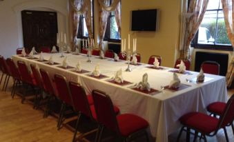 a long table with a white tablecloth and red chairs is set up in a room at The Imperial Hotel