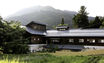 a traditional japanese house with a sloping roof and a view of the mountains in the background at Ryokan Warabino