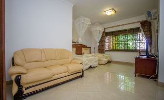 a spacious living room with a large beige couch and a bed , as well as a dining table and chairs at Hibis Hotel