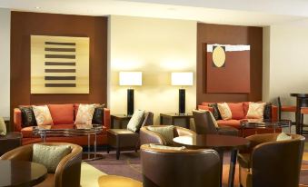 a modern hotel lobby with various seating options , including couches and chairs , as well as a coffee table at London Twickenham Stadium Hotel, a Member of Radisson Individuals