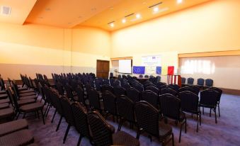 a large conference room with rows of chairs arranged in a semicircle , providing seating for a large group of people at Hotel Perla