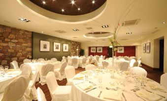 a large banquet hall with numerous round tables covered in white tablecloths and chairs arranged for a formal event at Columba Hotel Inverness by Compass Hospitality