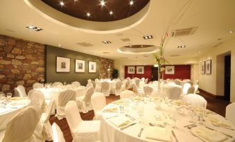 a large banquet hall with white tables and chairs , all set up for a formal event at Columba Hotel Inverness by Compass Hospitality