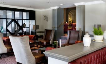 a modern living room with various seating options , including chairs and couches , arranged around a coffee table at Macdonald Berystede Hotel and Spa