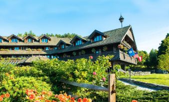 a large building surrounded by a lush green garden , with numerous flowers and plants in the foreground at Trapp Family Lodge