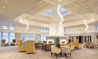 a large , well - lit hotel lobby with multiple couches and chairs arranged in a seating area at Coldra Court Hotel by Celtic Manor