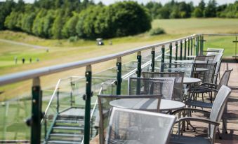 a golf course with several golf carts and umbrellas on the deck , providing a relaxing atmosphere for golfers at Greetham Valley