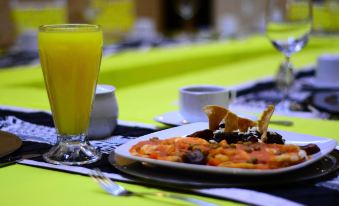 a dining table with a plate of food and a glass of orange juice on it at Hotel Imperial