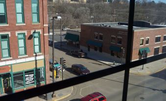 a view from a window shows a red car driving down a street next to buildings at Cobblestone Hotel & Suites - Chippewa Falls