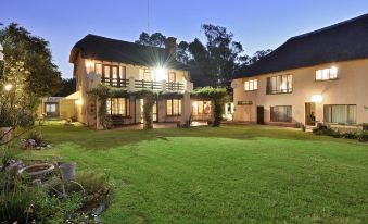 a large house with a well - maintained lawn and a tree in the front yard at night at The Cottage