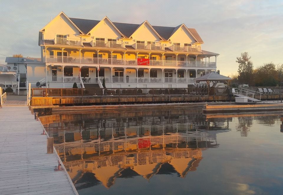 a large white building situated on the edge of a body of water , with a reflection of the building in the water at Sportsman's Inn Resort & Marina