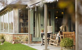 a patio with a wooden table and chairs , a brick wall , and green shutters is shown at The Welldiggers Arms