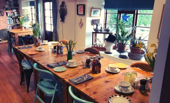 a wooden dining table is set with plates , cups , and a vase of flowers in the center at Mount Pleasant Farm