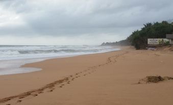 a sandy beach with footprints leading to the ocean , and a cloudy sky in the background at Sea Breeze