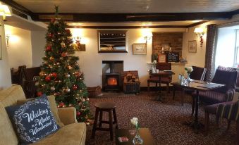 a cozy living room with a christmas tree , fireplace , and a brick fireplace in the corner at The Shepherds Inn