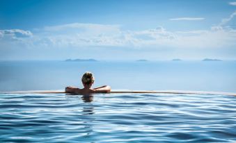 a man is floating on his back in a pool of water with a clear blue sky above at TUI BLUE Nha Trang