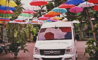 a white van parked in front of a colorful umbrella - covered building , surrounded by lush greenery at Shane Josa Resort