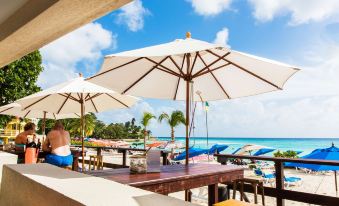 a beach scene with several people enjoying the sun and water , while lounging on chairs under umbrellas at Infinity on the Beach