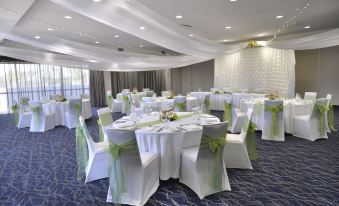 a well - decorated banquet hall with tables covered in white tablecloths and chairs arranged for a formal event at Rydges Palmerston - Darwin, an EVT hotel