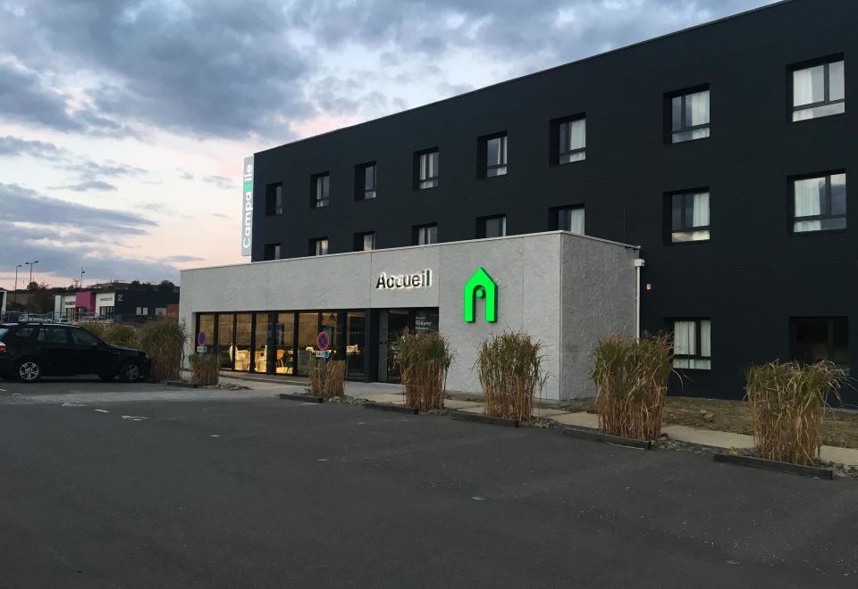 "a modern hotel building with a sign that reads "" quality inn "" prominently displayed on the front" at Campanile Laval Nord