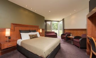 a large bed with a wooden headboard is in the middle of a room with purple carpeting and two chairs at Renmark Country Club