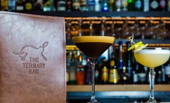 a bar counter with two drinks , a martini glass , and a menu , as well as a bottle of beer nearby at Novotel Sydney Darling Harbour