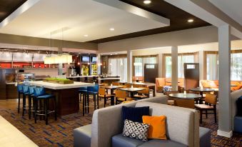 a spacious , well - lit restaurant with multiple dining tables and seating areas , as well as comfortable couches and chairs arranged around the dining table at Courtyard Pleasanton
