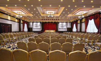 a large , empty conference room with rows of chairs and a stage set up for an event at Aston Karimun City Hotel
