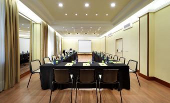 a large conference room with chairs arranged in a semicircle around a long table , and a projector screen mounted on the wall at Exe Salamanca