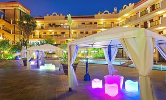 a large building with a pool in front of it , illuminated by colorful lights at night at Elba Castillo San Jorge & Antigua Suite Hotel