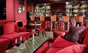 a cozy red living room with various furniture , including couches , chairs , and a dining table at Westminster Hotel