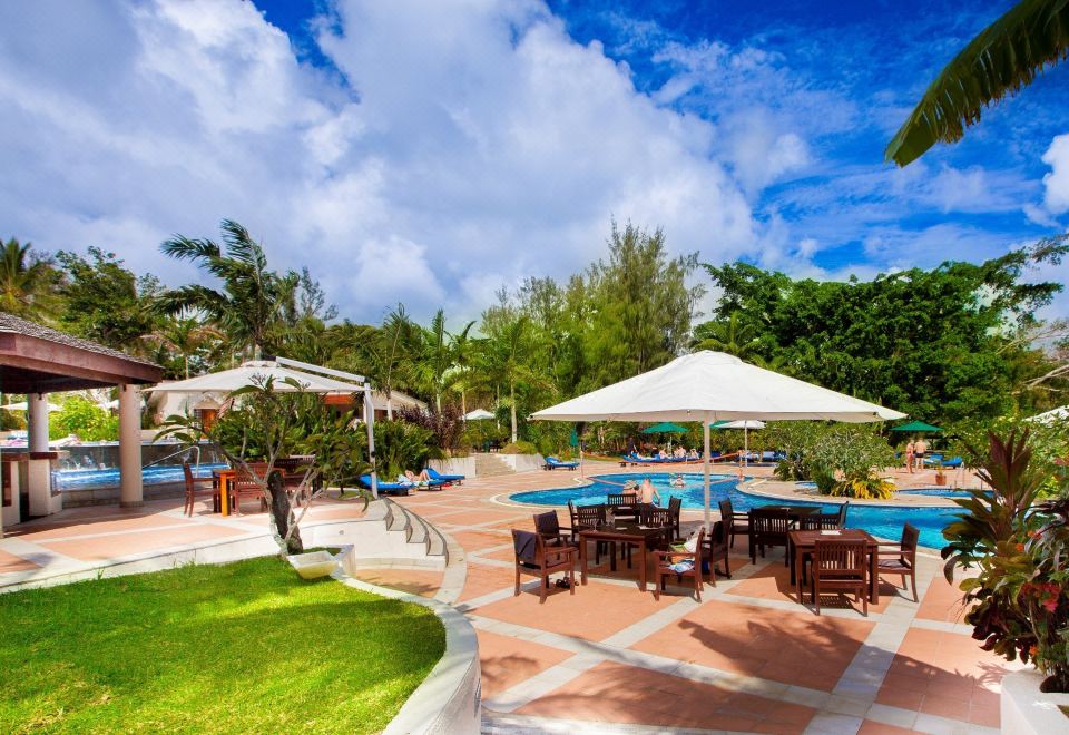 a large outdoor pool surrounded by chairs and umbrellas , providing a relaxing atmosphere for guests at Warwick le Lagon Resort & Spa, Vanuatu