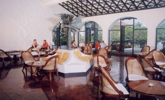 a large , open - air restaurant with white walls and wooden floors , featuring several people sitting at tables and enjoying their meals at Neptune