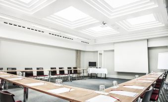 a large , empty conference room with multiple rows of chairs arranged in a semicircle around a table at Hotel Weitzer Graz