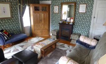 a living room with a fireplace , floral wallpaper , and wooden furniture , including two couches and a coffee table at The Birchwood Inn