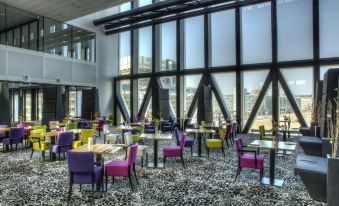 a large room with colorful chairs and tables , creating a vibrant atmosphere in the space at Fletcher Wellness-Hotel Leiden