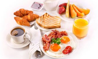 a breakfast table with various food items , including eggs , bacon , toast , and orange juice , accompanied by a cup of coffee at Villa Marina
