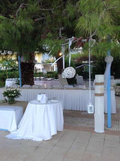 a well - decorated outdoor dining area with white tablecloths , chairs , and a round table set for a special event at Hotel Summery