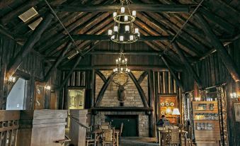 a rustic restaurant with wooden beams , stone fireplaces , and chandeliers hanging from the ceiling , giving it an old - world charm at Pine Mountain State Resort Park