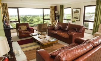 a spacious living room with a large window and brown leather furniture , including two couches and a coffee table at Peartree Hill