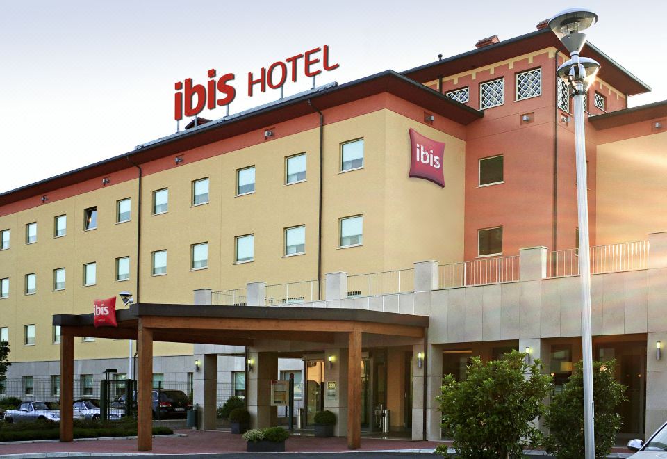 "a large hotel with a sign that says "" ibis "" and a covered entrance , situated in a city" at Ibis Como