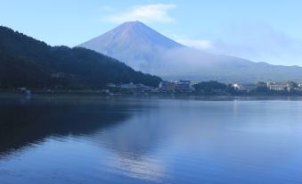 A large body of water with mountains in the background is reflected on an island under a blue sky at Fuji Ginkei