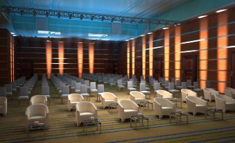 a large , empty auditorium with rows of white chairs and a stage at the front at Marina Hotel