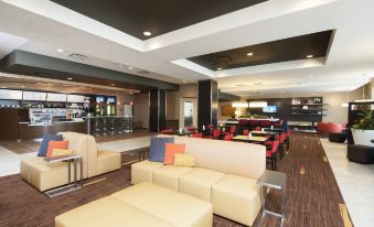 a modern lounge area with yellow couches , red chairs , and a bar in the background at Courtyard Peoria Downtown