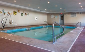 a large indoor swimming pool with blue tiles , surrounded by benches and umbrellas for seating at Holiday Inn Express Newington - Hartford