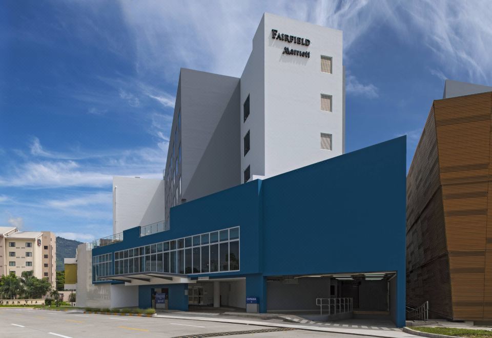 "a large white building with a blue roof and the word "" fairfield "" on it is surrounded by other buildings" at Fairfield by Marriott San Salvador