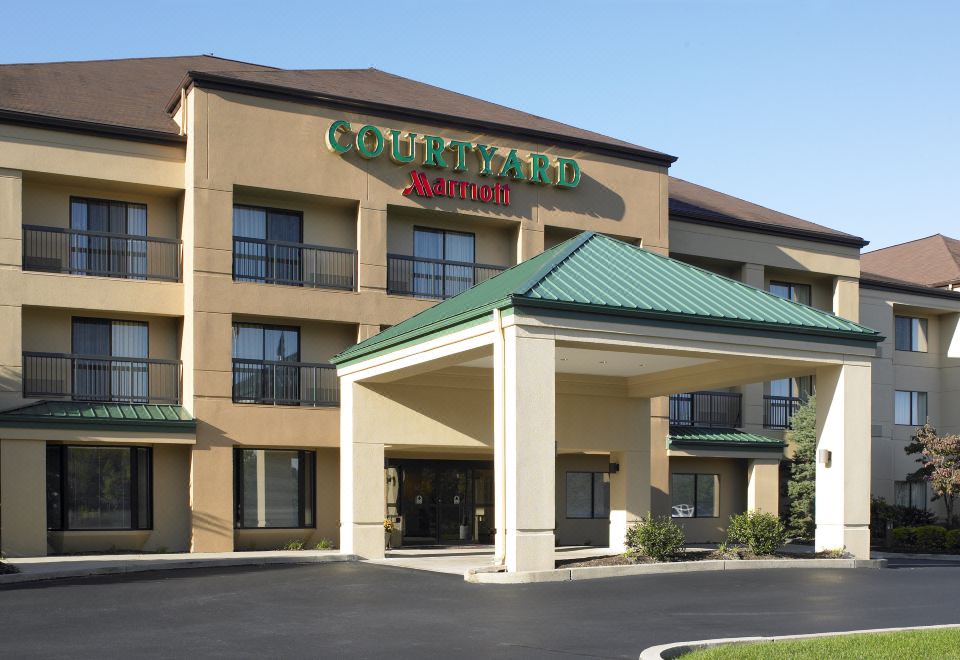 a courtyard by marriott hotel with its name displayed above the entrance , surrounded by a brick building and trees at Courtyard by Marriott Scranton Montage Mountain