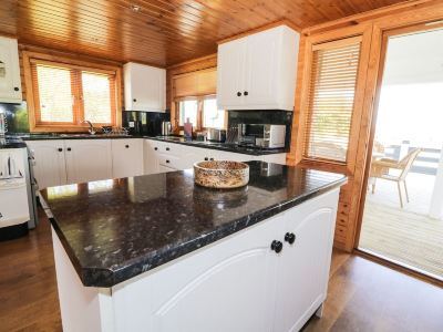 a kitchen with white cabinets and a black countertop has a microwave on the counter at Moon Face