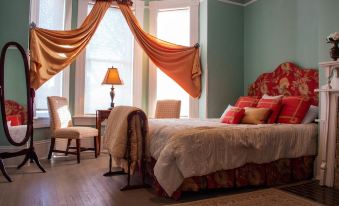 a cozy bedroom with a large bed draped in orange drapes , creating a warm and inviting atmosphere at Peacock Place