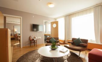 a living room with a white coffee table , brown leather chairs , and a large window at Scandic Linköping City